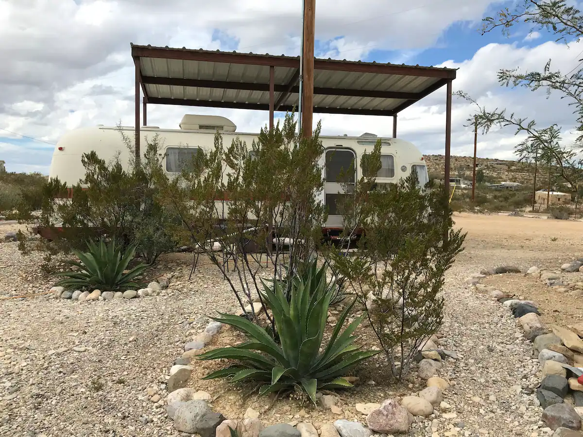 A desert scene with an rv and plants.